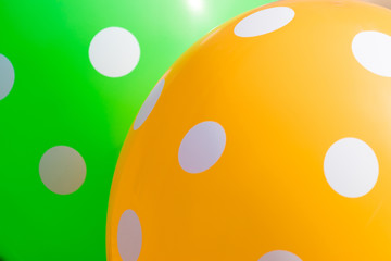 Fototapeta premium Background of green and orange balloons with the white circles on them. The optimistic picture, the symbol of happiness and joy