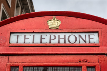 Traditional old style UK red phone box (booth) in London, England, United Kingdom - close up in cloudy weather