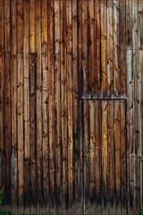 a close-up of a wall of small planks and the door in the wall