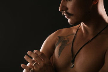 Close up unrecognizable male model, shortless cute torso with tanned skin and tattoo on black...
