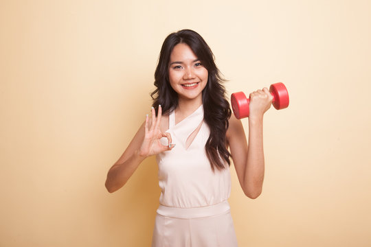 Healthy Asian woman show OK with dumbbells.