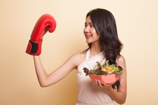 Young Asian woman with boxing glove and salad.