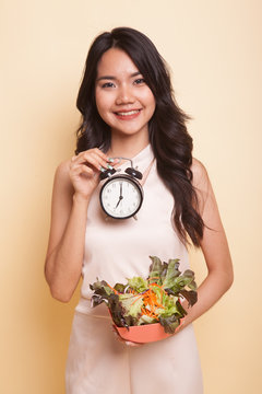 Young Asian woman with clock and salad.