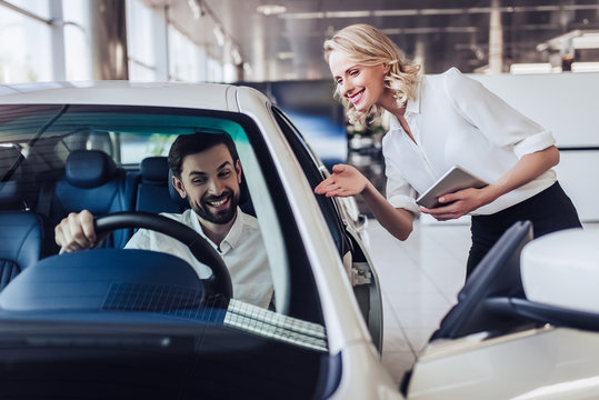 saleswoman showing to client car in dealership salon