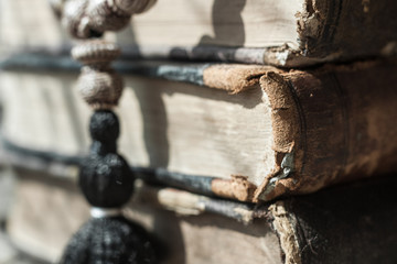 Beads lying on shabby battered old book lying on the old cracked wood