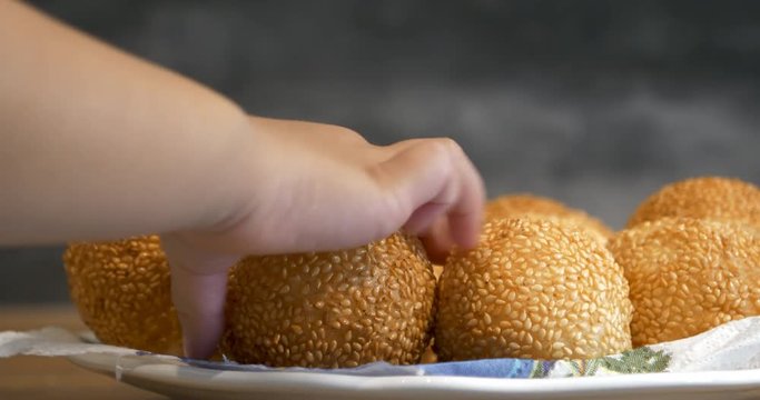 Close view of a kid hand pick up a traditional asian style glutinous rice ball to eat, from a plate, 4K