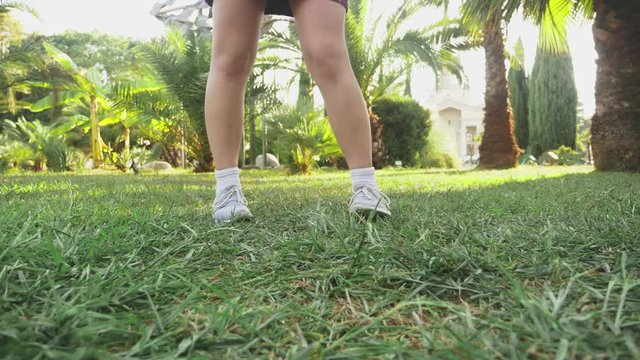 young beautiful red-haired girl dancing in the park. woman in a mini skirt dancing in a tropical park on a background of palms. 4k, slow motion