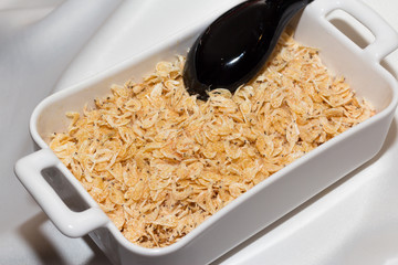 Dried shrimp in white ceramic bowl served with black spoon