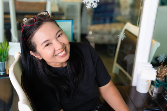 Happy middle ege asian woman with eye glasses smiling in cafe