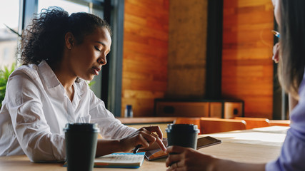 Business woman listening to her female colleague during sitting in cafe