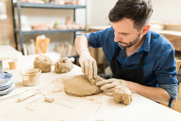 Artist Using Sponge To Smooth Clay In Pottery Workshop