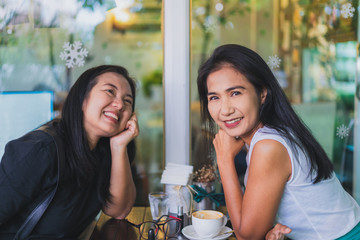Two asian woman enjoy talking and drinking coffee in cafe