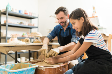 Instructor Assisting Student In Making Pottery