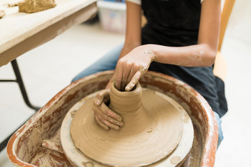 Midsection Of Girl Making Clay Pots On Potter Wheel