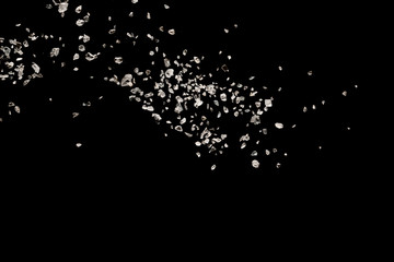 Split debris of stone exploding against black background.