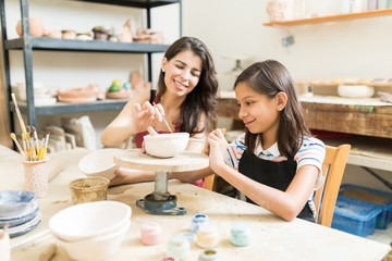 Obraz na płótnie Canvas Teacher Assisting Girl To Unleash Her Creativity Of Pottery Painting