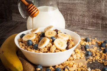 Healthy breakfast concept with oat flakes and fresh berries on rustic background. Food made of granola and muesli. Healthy banana smoothie with blackberries, honey and milk.