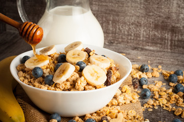 Healthy breakfast concept with oat flakes and fresh berries on rustic background. Food made of granola and muesli. Healthy banana smoothie with blackberries, honey and milk.