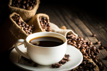 Coffee cup and beans on a rustic background. Coffee Espresso and a piece of cake with a curl. Cup of Coffee and coffee beans on table.