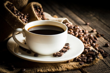 Coffee cup and beans on a rustic background. Coffee Espresso and a piece of cake with a curl. Cup of Coffee and coffee beans on table.