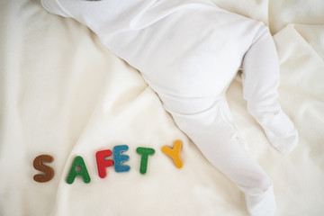 Safety text wooden word top view on blanket with baby body and copy space background