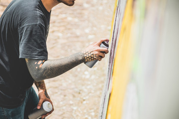 Tattoo graffiti writer painting with color spray his picture on the wall