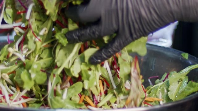 Green salad prepared in slow motion with carrots, leafs, lattuce and sprouts