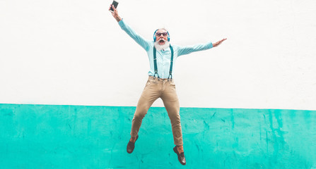 Senior crazy man jumping and listening music outdoor