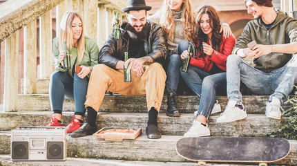 Young millennials friends drinking beer and eating pizza outdoor in city center