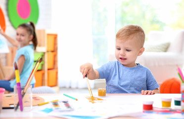 Obraz na płótnie Canvas Little boy and blurred girl painting indoors
