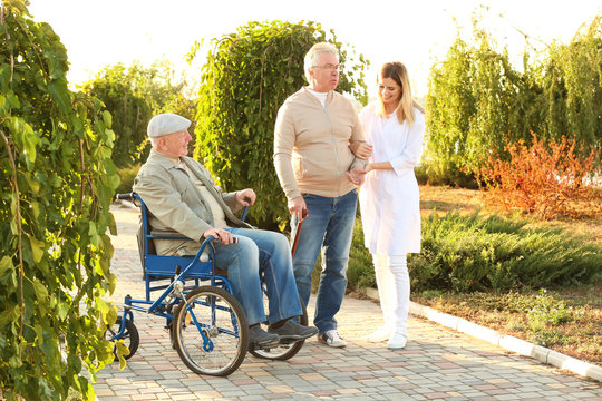 Nurse from care home walking with senior people outdoors