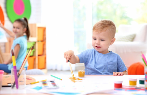 Little boy and blurred girl painting indoors