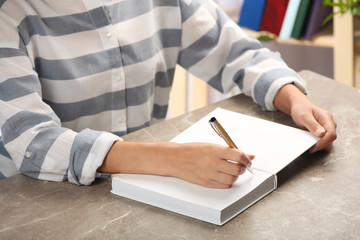 Writer signing autograph in book at table, closeup