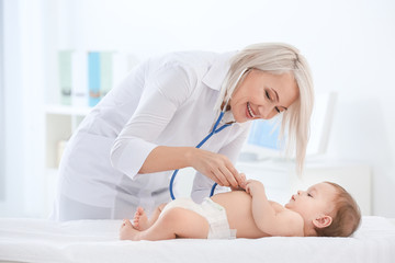 Obraz na płótnie Canvas Mature female doctor examining baby boy in clinic