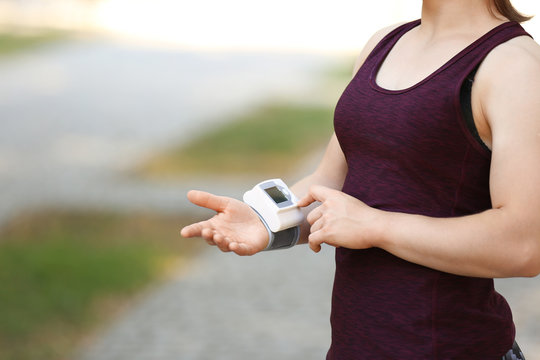 Young woman checking pulse after workout, focus on hands