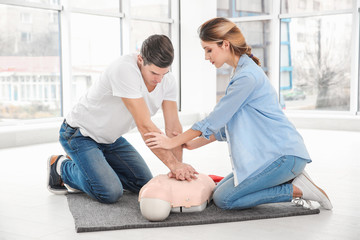 Young man practicing CPR on mannequin in first aid class