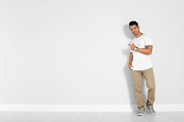 Full length portrait of handsome young man and space for text on white wall background