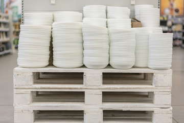 Fototapeta na wymiar Many plates on the shelf of the store white set cooking. Shelves in a variety of white plates in the store. Kitchen porcelain