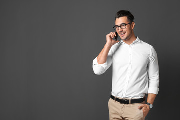 Handsome young man talking on phone against black background. Space for text