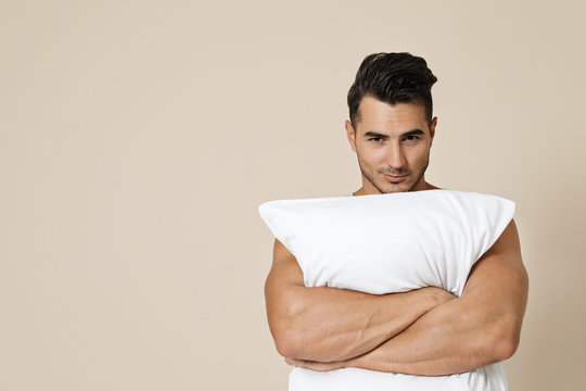 Young Man With Soft Pillow On Color Background