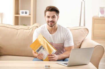 Young man unpacking parcel at home