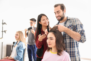 Professional hairdresser and trainees working with clients in salon. Apprenticeship concept