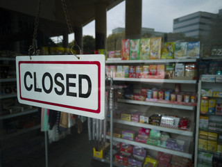 Close-up shot of a closed signage hanging on a glass door of a convenience store