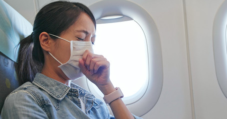Fototapeta na wymiar Woman feeling unwell and wearing face mask on plane