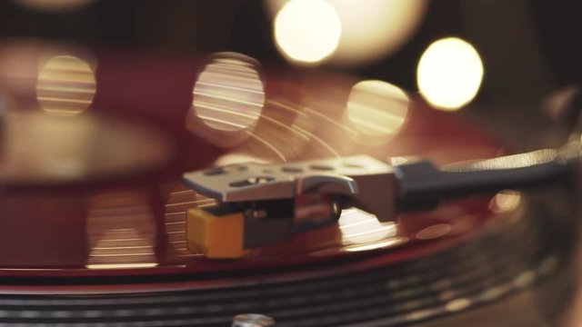 A slide turntable vinyl record player. The vinyl record on DJ turntable record player close up. The stylus smoothly with a needle onto a rotating red vinyl plate. Included gramophone and torque plate 