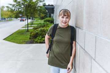 Happy teenage girl leaning against brick wall.