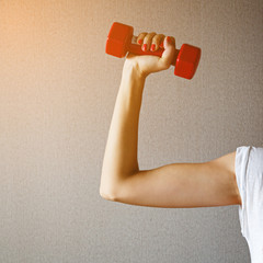 Woman hand holding red dumbbell on gray background