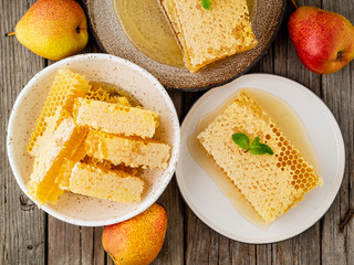 honey in honeycomb, close-up, on brown ceramic plate, on old gray wooden rustic table, top view