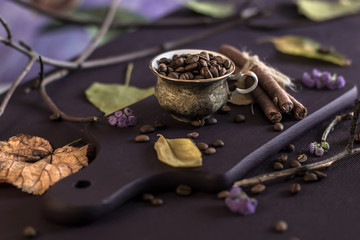 Still life. The coffee beans in the cup are decorated with autumn leaves and twigs.