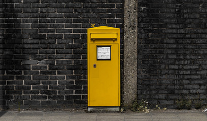 Gelber Postkasten vor einer Mauer - obrazy, fototapety, plakaty